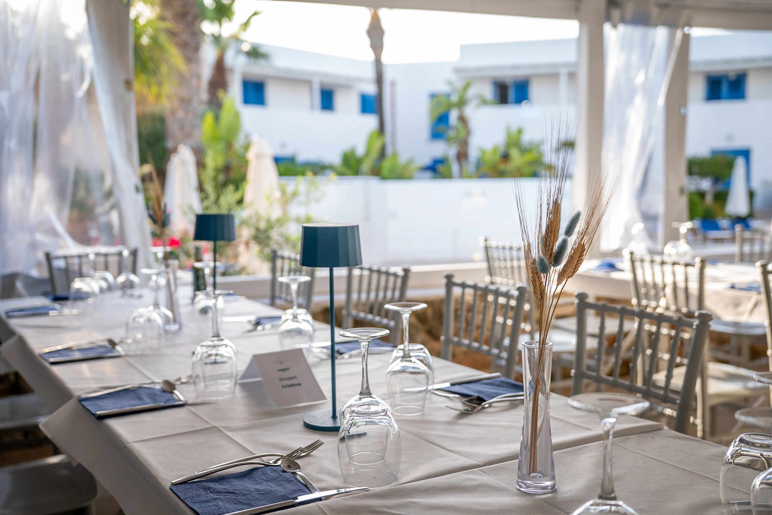 Tavolo del ristorante Poseidon apparecchiato con calici e lampada blu